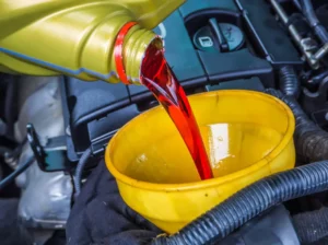 Red transmission car fluid pouring into a funnel