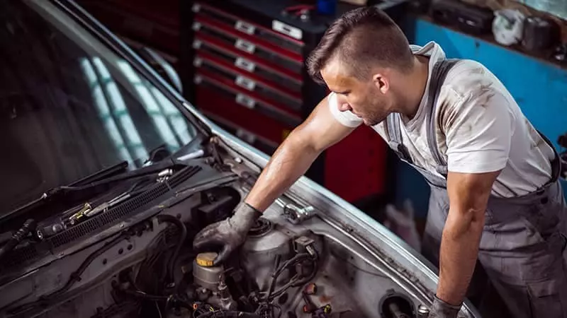 A mechanic professionally checking the different types of fluids in a car.